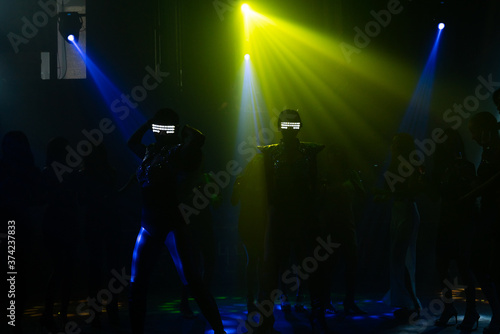 Silhouette confidence woman with LED glowing glasses dancing to the music with multi-color illuminated at nightclub. Group of beautiful woman enjoy nightlife drinking alcohol and dancing to the music.