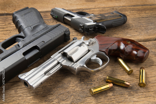 Revolver and automatic hand guns on wooden background