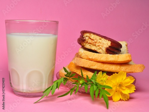 Dry rusk bread, choco pie chocolate and a glass of milk isolated on pink background. Healhty breakfast menu