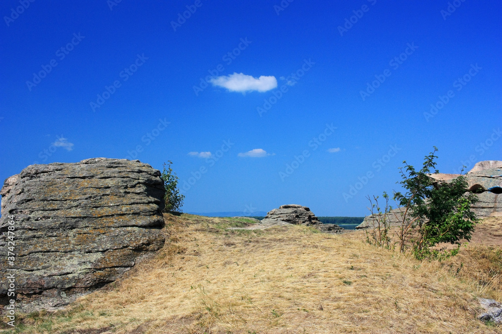 Stone granite rocks in the steppe under the blue sky