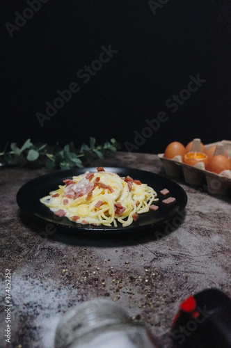 Spaghetti Carbonara in black plate on table in restaurant.