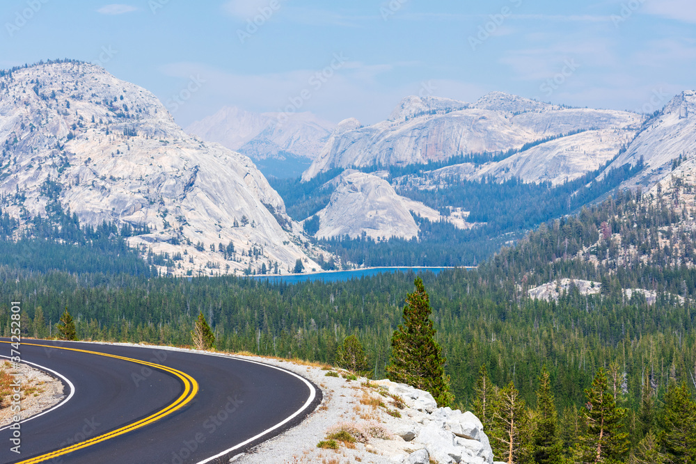 Empty Tioga Pass road running through Sierra Nevada mountain scenery on sunny day in summer near Olmsted Point in Yosemite National Park