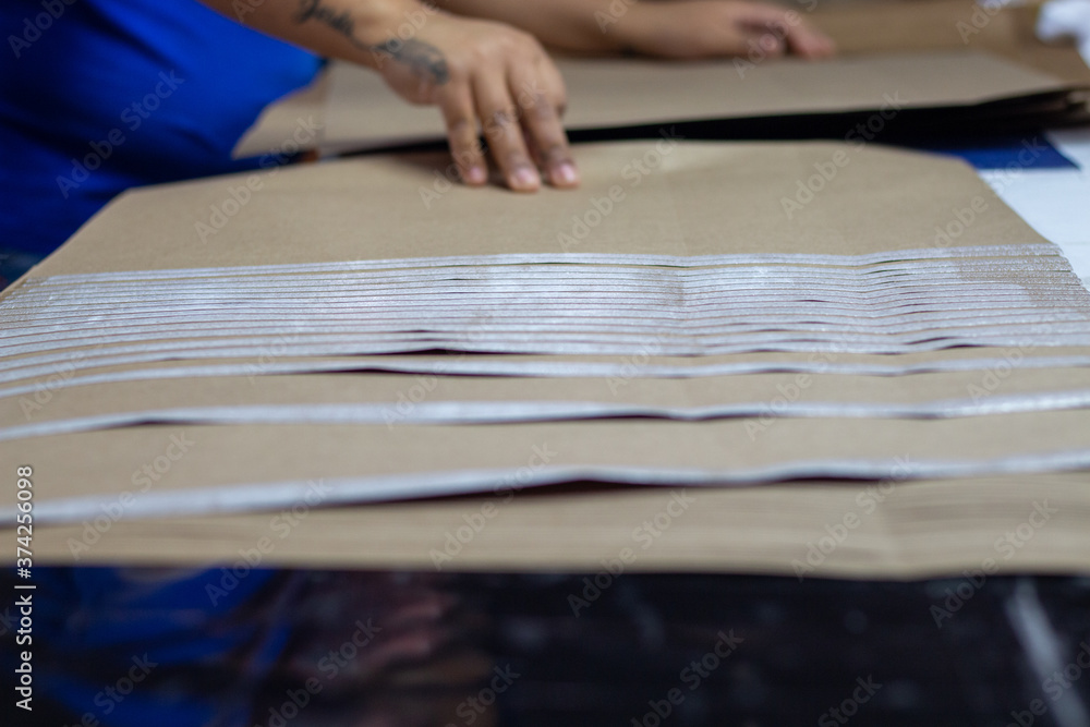 Mano trabajando con papeles con pegamento listos para doblarse en una fábrica de imprenta Mano trabajando con papeles con pegamento listos para doblarse en una fábrica de imprenta