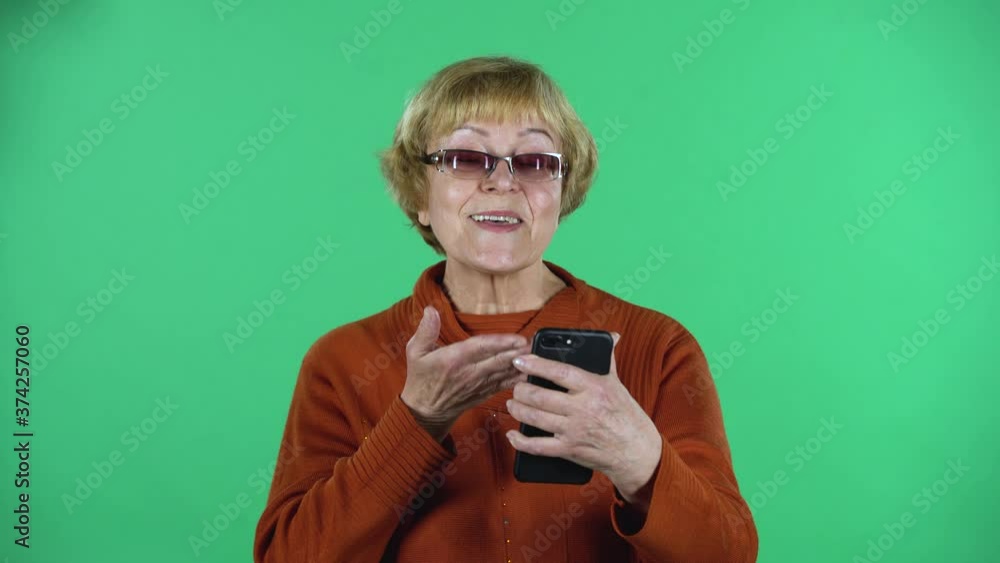Portrait of senior woman is talking for video chat using mobile phoneisolated over green background. Portrait of senior woman is talking for video chat using mobile phoneisolated over green background.
