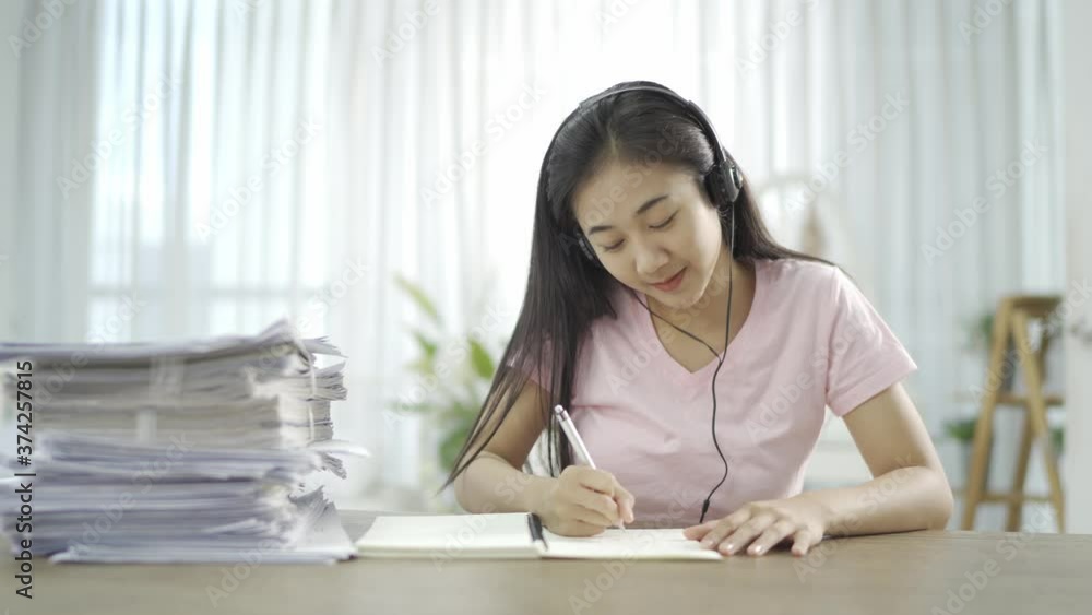 Young Asian woman wears headset conference calling on laptop talks with online teacher studying, working from home. Lady student e learning using computer webcam Young Asian woman wears headset conference calling on laptop talks with online teacher studying, working from home. Lady student e learning using computer webcam