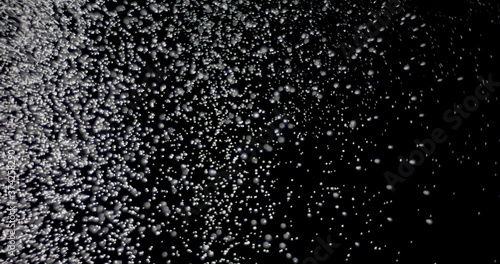 White snowflakes falling in slow motion against an isolated black background.