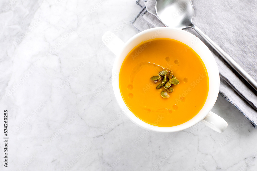Pumpkin soup in white bowl on marble table. Autumn seasonal soup dish. Top view, copy space Pumpkin soup in white bowl on marble table. Autumn seasonal soup dish. Top view, copy space