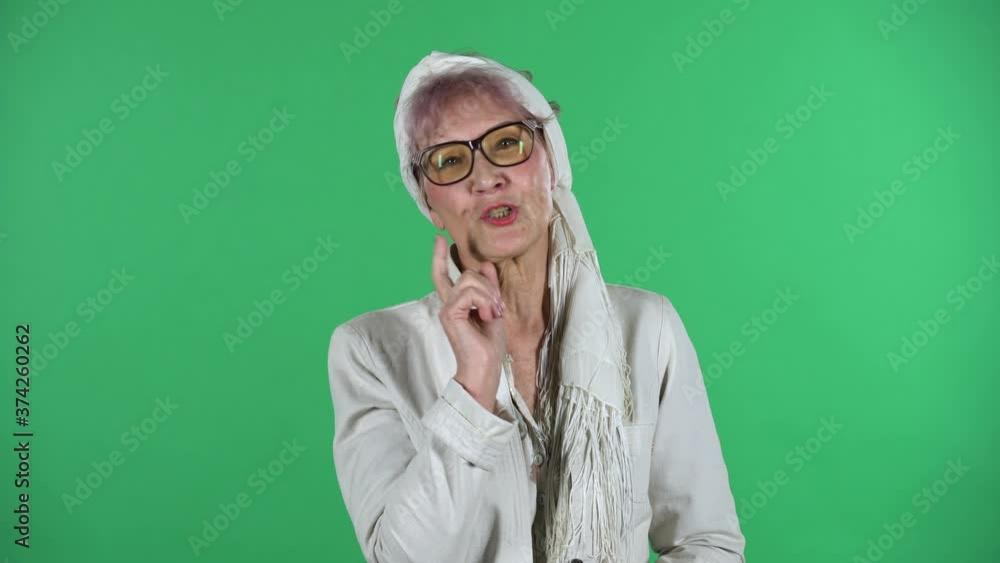 Portrait of old stylish woman is communicates with someone in a friendly manner isolated over green background. Portrait of old stylish woman is communicates with someone in a friendly manner isolated over green background.