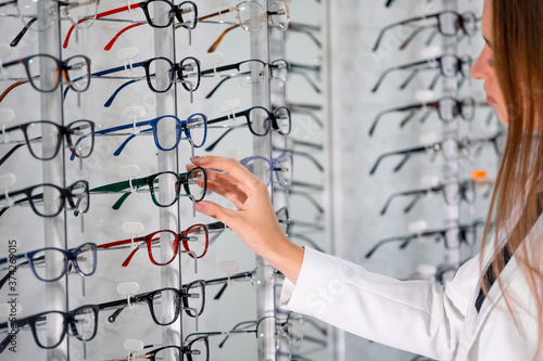 Showcase with spectacles in modern ophthalmic store. Woman hands with glasses. Closeup. © Vadim