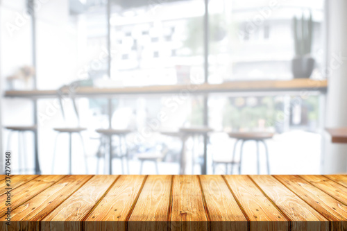 Empty wooden desk space and blurry background of cafe or Restaurant for product display montage © qOppi