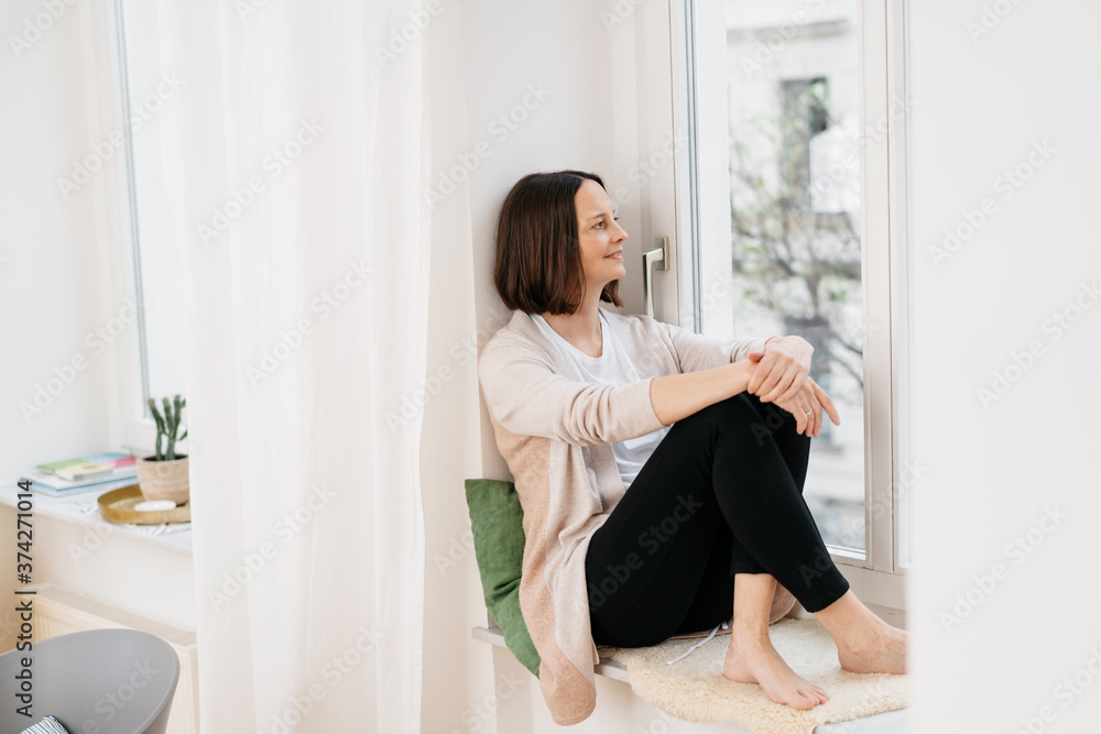 Woman relaxing in a windowsill looking outdoors Woman relaxing in a windowsill looking outdoors