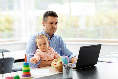 remote job, multi-tasking and family concept - middle-aged father in earphones with baby working at home office