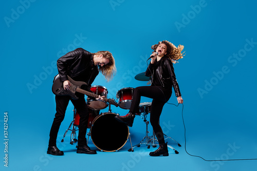Full length photo of crazy funky two people rock band team man play bass guitar woman sing mic song solo popular rhythm isolated over bright shine color background