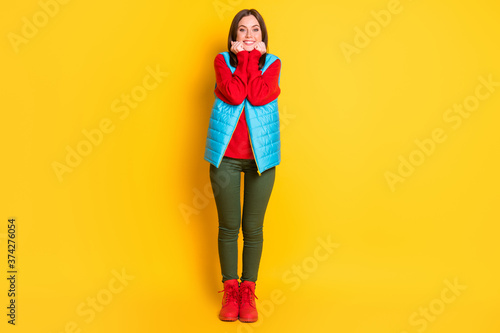 Full body size photo of charming lovely young lady relaxing look hands cheekbones face beaming smiling wear green pants blue vest red sweater boots isolated bright yellow color background