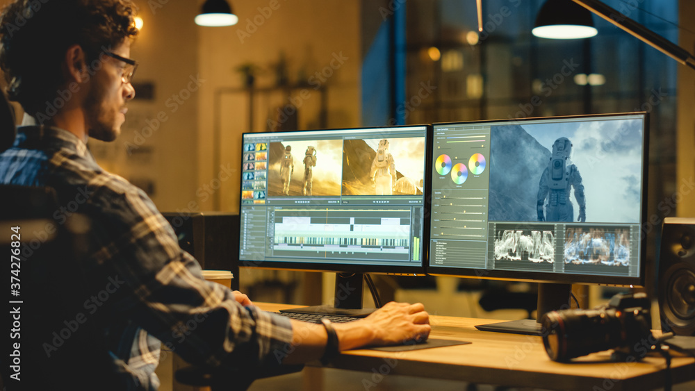 © Gorodenkoff - Late Evening Creative Office: Professional Videographer Works on Desktop Computer, Doing Footage Montage, Using Video Editing Software. Modern Video Developers Office