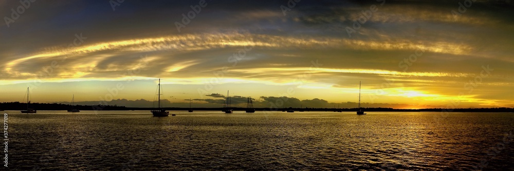 Yellow and gold coloured cirrostratus cloudy coastal nautical Sunset Seascape panorama. Tin Can Bay, Queensland, Australia.