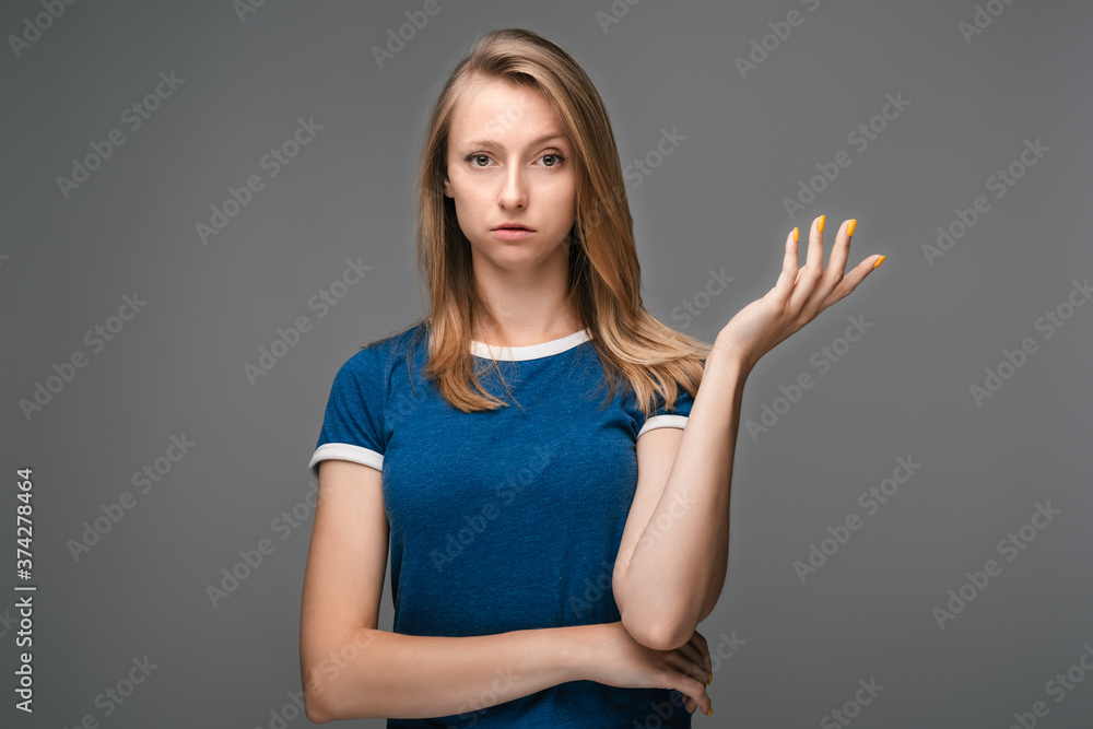 Studio shot of frustrated female with blonde straight hair gesturing with raised palm Studio shot of frustrated female with blonde straight hair gesturing with raised palm