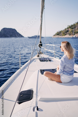 Luxury travel on the yacht. Young happy woman on boat deck sailing the sea. Yachting in Greece.