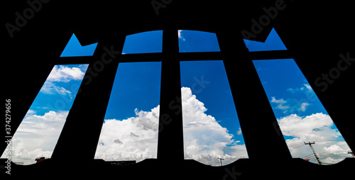 Low angle view of h=white cotton clouds against silhouetted window frame.