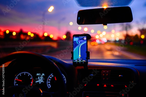 Fototapeta kuchenna Smartphone with map on the screen in car. Automobile dashboard in night mode.