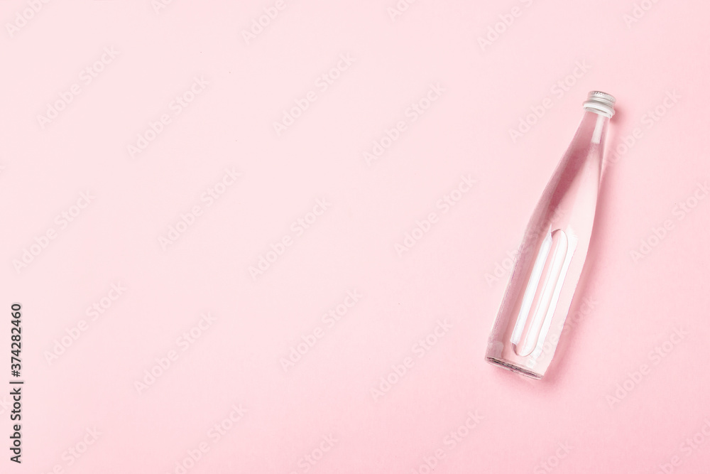 Glass bottle with clear water on a pink background. Concept of health care, water balance, beauty and health. Banner. Flat lay, top view Glass bottle with clear water on a pink background. Concept of health care, water balance, beauty and health. Banner. Flat lay, top view