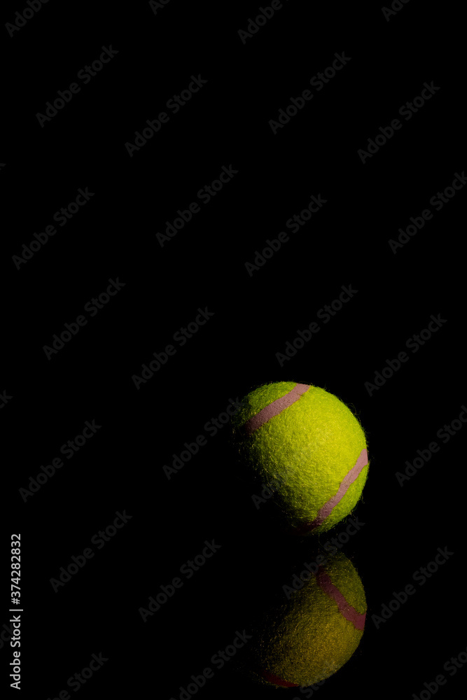 Bright Yellow Tennis Ball on dark mirror with reflections