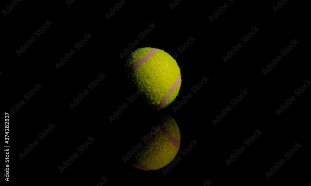 Bright Yellow Tennis Ball on dark mirror with reflections