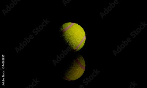 Bright Yellow Tennis Ball on dark mirror with reflections © Sunshine Seeds