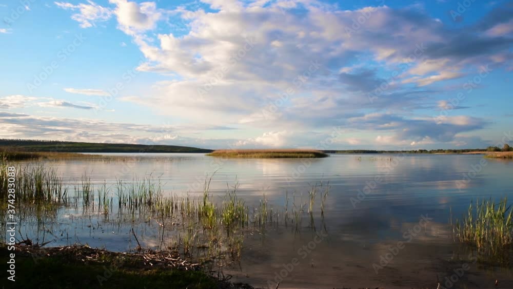 Dramatic blue evening tranquil sunset sky over dry grass field at pond lake shore. Rural countryside serene cloudscape reflection ripple water surface Dramatic blue evening tranquil sunset sky over dry grass field at pond lake shore. Rural countryside serene cloudscape reflection ripple water surface