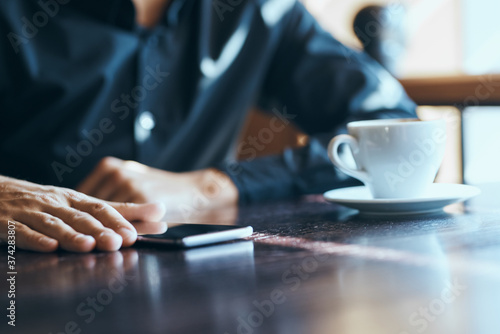 Businessman with mobile phone in cafe at table, cropped view