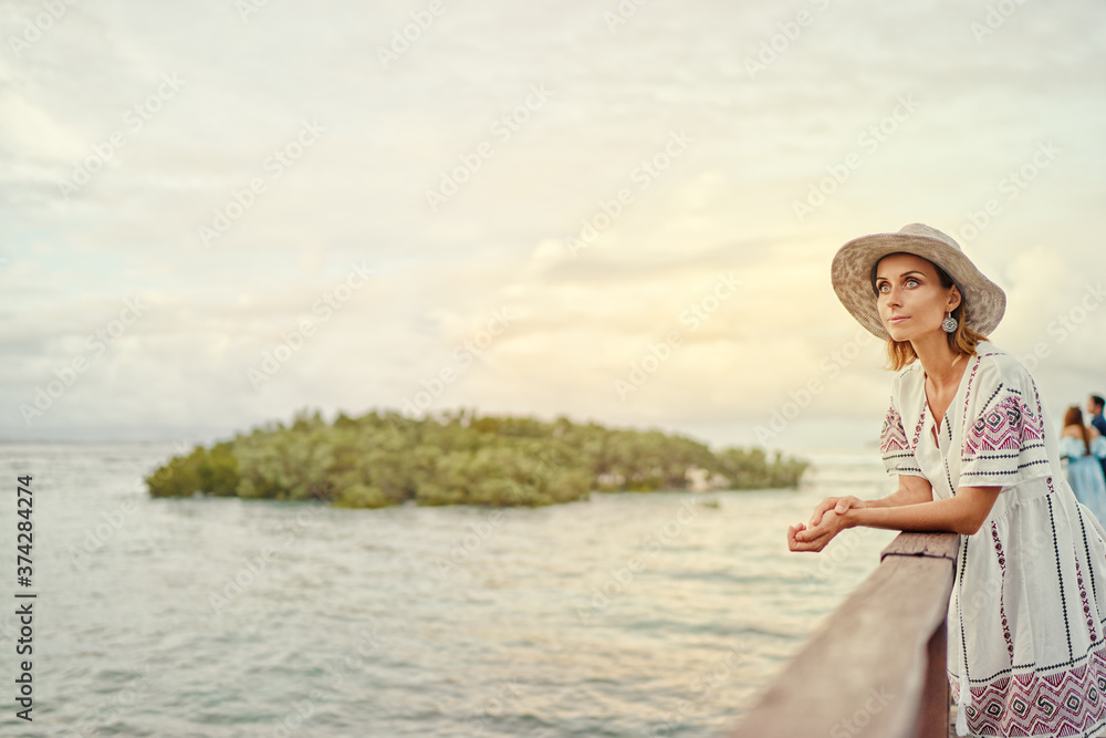Vacation on tropical island. Woman in hat enjoying sea view from wooden terrace. Vacation on tropical island. Woman in hat enjoying sea view from wooden terrace.