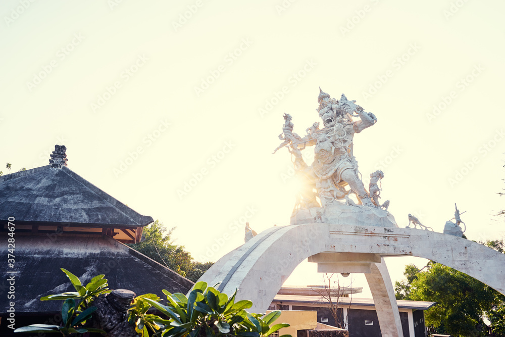 A statue on an arc pedestal depicting a bunch of monkeys fighting with a scary looking warrior.  Bali, Indonesia.