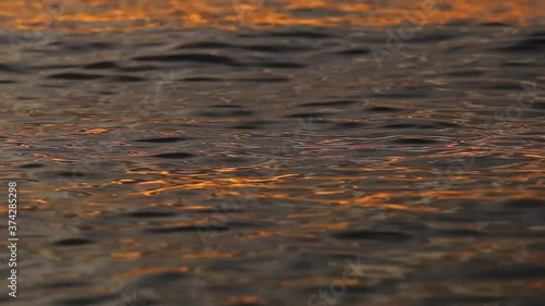 Abstract shot of moving waves surface in golden sea waters of Baikal lake