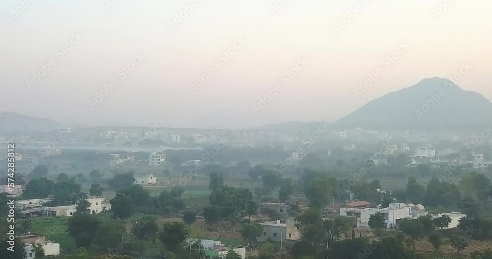 Drone Flying Over The Beautiful Landscape In Pushkar, Rajasthan With Lush Trees And Residential Houses. Distant View Of A Majestic Mountain In The Misty Background - aerial Drone Flying Over The Beautiful Landscape In Pushkar, Rajasthan With Lush Trees And Residential Houses. Distant View Of A Majestic Mountain In The Misty Background - aerial