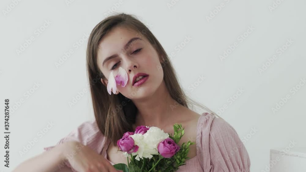 Attractive beautiful young woman model with flowers looking and posing at camera Attractive beautiful young woman model with flowers looking and posing at camera