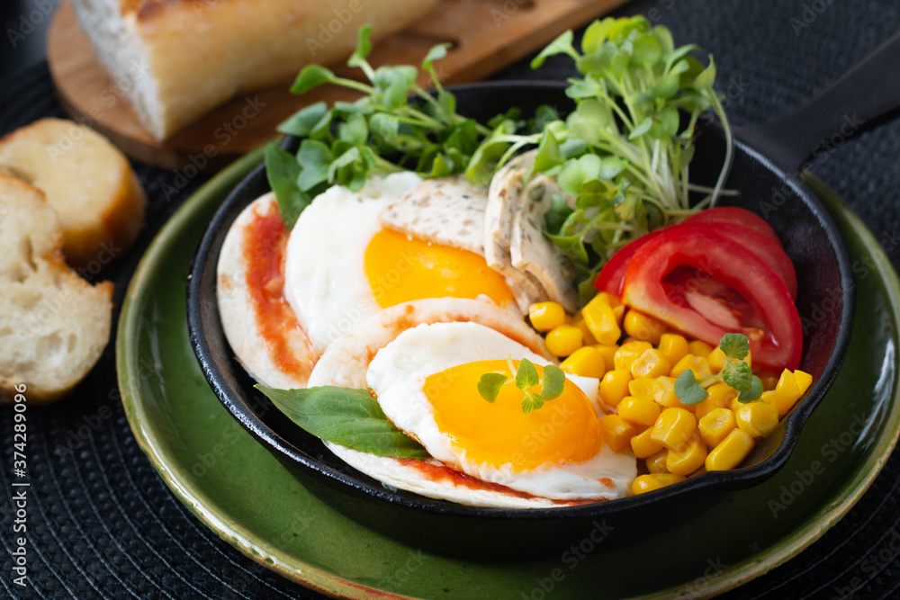 Healthy food Super Breakfast concept  fried eggs and micro-green salad with corn and tomato in Skillet iron pan with copy space