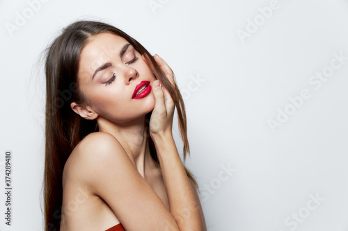 Girl naked shoulders closed eyes red lips hand on face skin care 
