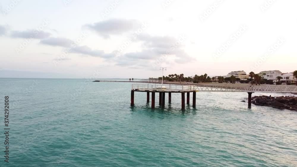 Vista aérea de drone sobre el mar con un hermoso paseo de madera al fondo la playa y la espectacular puesta de sol Vista aérea de drone sobre el mar con un hermoso paseo de madera al fondo la playa y la espectacular puesta de sol