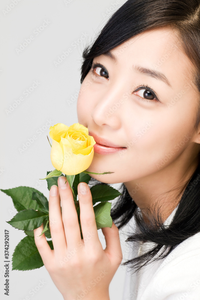 close up of young woman holding yellow rose