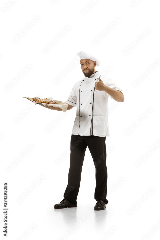 Cooker, chef, baker in uniform isolated on white studio background with croissants. Young man, restaurant cooker's portrait. Business, foor, professional occupation, emotions concept. Copyspace for ad Cooker, chef, baker in uniform isolated on white studio background with croissants. Young man, restaurant cooker's portrait. Business, foor, professional occupation, emotions concept. Copyspace for ad