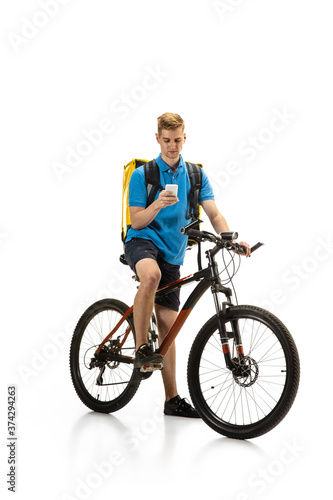 Scrolling phone. Deliveryman with bicycle isolated on white studio background. Contacless service during quarantine. Man delivers food during isolation. Safety. Professional occupation. Copyspace for