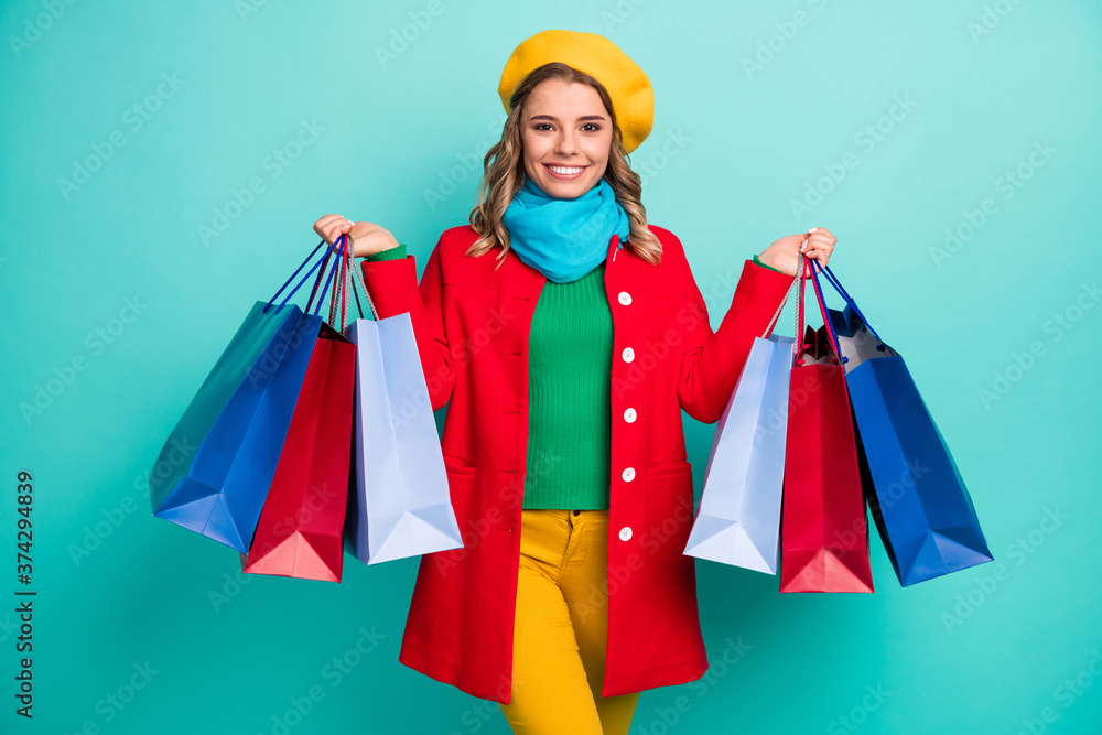 Portrait of positive cheerful girl have travel trip enjoy shopping hold many bags wear red blue yellow sweater trousers isolated over turquoise color background