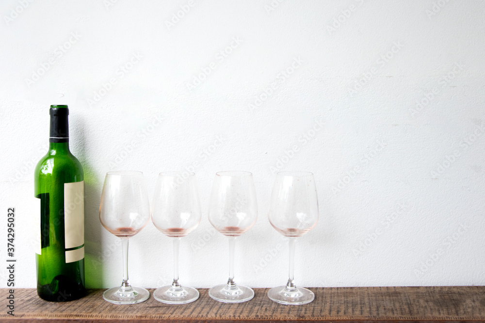 bottle of wine and glass on white wall