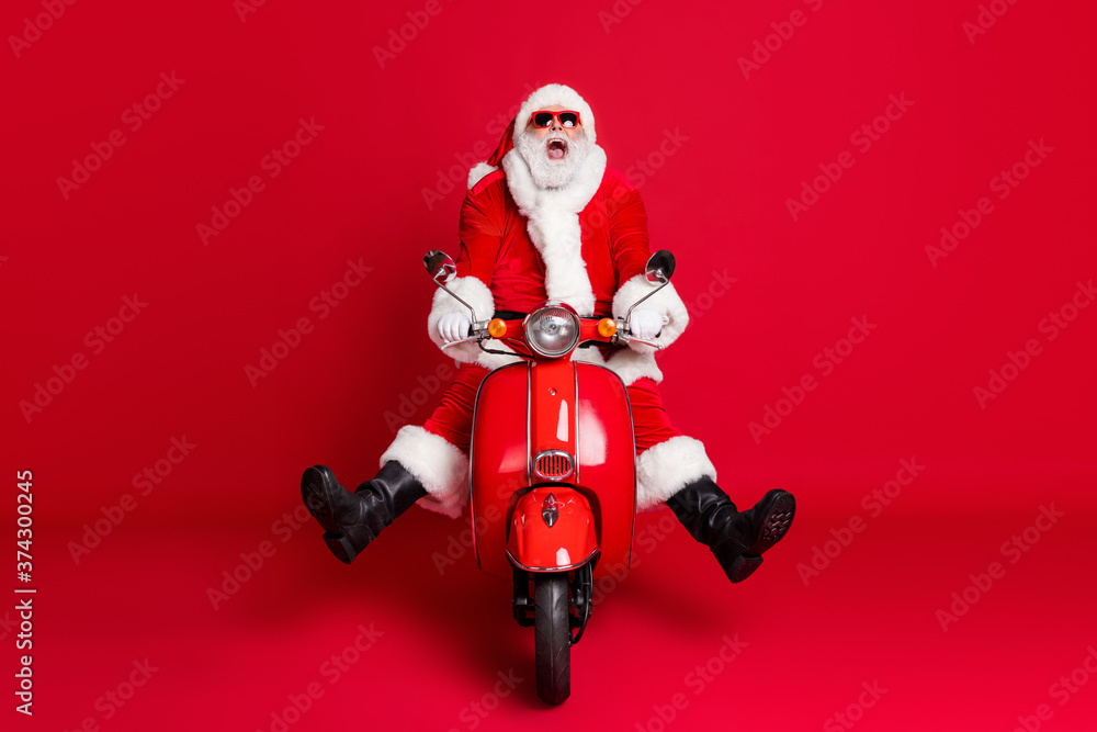 Full length photo of retired grandfather white beard mad ride retro moped open mouth spread legs fast ride down hill wear x-mas costume coat sunglass cap isolated red color background Full length photo of retired grandfather white beard mad ride retro moped open mouth spread legs fast ride down hill wear x-mas costume coat sunglass cap isolated red color background