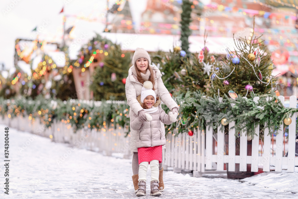 Cheerful family, mother and little girl having fun on Christmas market.