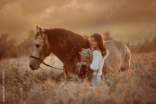 Beautiful  young woman on spanish buckskin horse in rue field at sunset