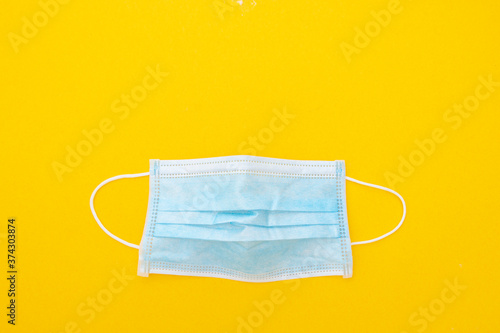 Surgical face mask to cover the mouth and nose. Protection concept. Yellow background, top view.