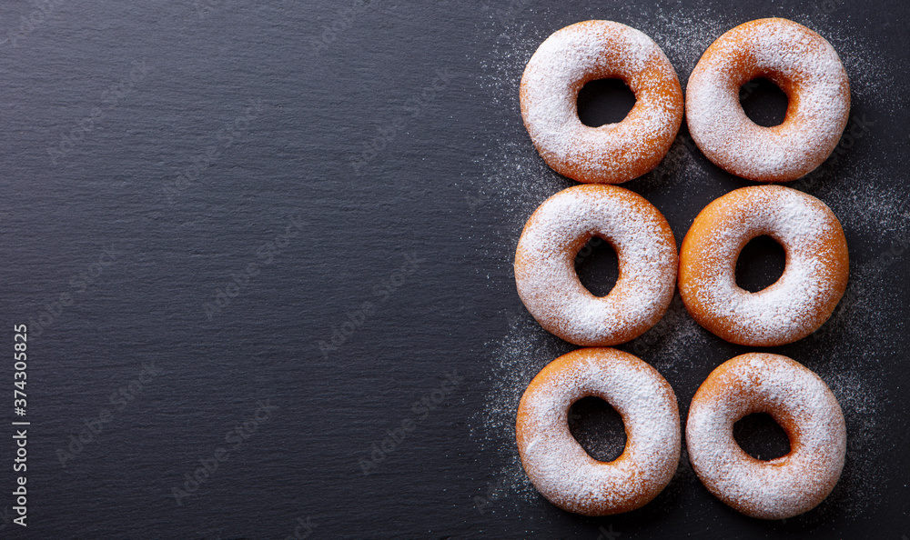 Donuts with sugar powder on slate board. Flat lay composition. Copy space. Top view. Donuts with sugar powder on slate board. Flat lay composition. Copy space. Top view.