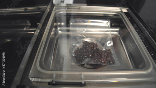 Close up of automated vacuum seal machine packing coffee beans in plastic bag