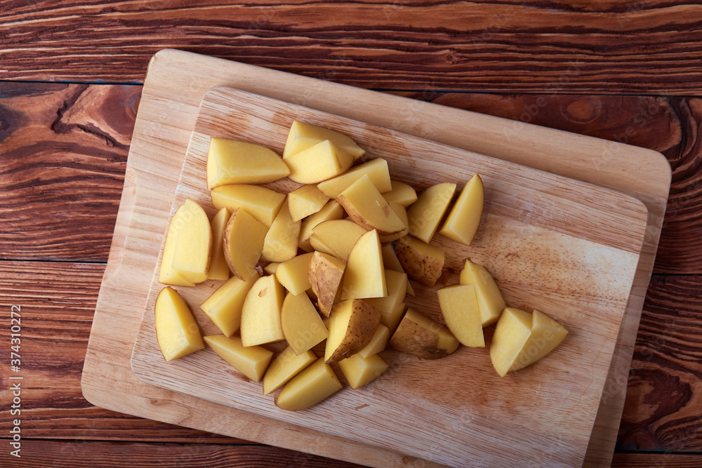 Serving of slices raw potatoes on wooden cutting boards and wooden rustic table. Top view. Serving of slices raw potatoes on wooden cutting boards and wooden rustic table. Top view.